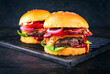 © HLPhoto - Classical cheeseburger with beef patty, cheese and bacon served as close-up with onion rings and tomato ketchup on a rustic grillage