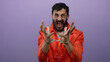 © Krakenimages.com - Hispanic man in prison jumpsuit passionately gestures in handcuffs against a purple backdrop, emphasizing incarceration emotion and justice themes.