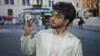 © Krakenimages.com - Young man with beard in white coat holding optometry glasses on a street with italian flag in background examining eyewear.