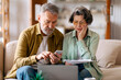 © Home-stock - Upset elderly couple checking financial documents and bills, calculating family budget, reading loan papers, sitting on couch at home