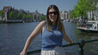© Krakenimages.com - Woman enjoying sunlight by amsterdam canals with historic architecture in the background, wearing sunglasses, capturing a relaxed moment in the urban outdoors of the netherlands.
