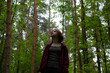 © Anastasia.photoyoga - Beauty face emotional woman looking up on a green pine trees in the forest on sun spring weather. Girl walking in fashion dress, breath fresh air. Closeup portrait.  Focus on facial expressions