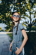 © SHOTPRIME STUDIO - lifestyle woman in modern boho-western denim street style smiling joyfully outdoors with film color tone, sunglasses, and braided hair under bright sunlight