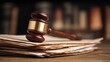 © Chanoknan - Wooden Gavel on Stack of Legal Papers with Blurred Law Books in Background Representing Justice and Legal Practice
