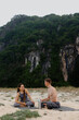 © Mirrorstudio - Young caucasian couple relaxing on beach with scenic cliffs in background