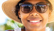 © theshooter - Una mujer joven guapa sonriente con gafas de sol y sombrero protegiéndosela del sol durante vacaciones de verano