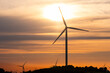 © yaqui_villegas - Wind turbines turning at sunset in Catalonia, silhouetted against warm skies, representing renewable power, sustainable energy and environmental preservation.