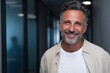 © Rifqi - Cheerful mature professional businessman portrait smiling genuinely in modern office hallway expressing confidence happiness and positive attitude a symbol of leadership success