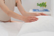 © HalynaRom - A person gently arranges a fluffy white pillow on a neatly made bed in a well-lit, inviting bedroom. Tactile closeness and inner peace concept