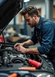 © Ilya - Caucasian male mechanic in blue uniform repairing car engine in workshop