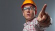 © sambath - A man in a hard hat and safety glasses pointing at the viewer with his index finger.