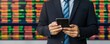 © justjupiter - ESG, Environment and Investment Businessman using smartphone with stock market data in the background.