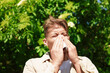 © New Africa - Young man with paper tissue suffering from seasonal pollen allergy near blossoming tree on spring day