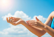 © PictoAi - Moisturizing and smooth skin A woman applying sunscreen to her arms. Against a bright blue sky with scattered clouds and bright sun