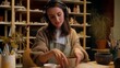 © Yuliia - Caucasian relaxed woman girl female potter modeling clay process in workshop pottery hobby smiling sculptor designer listen music audio in headphones ceramics art therapy creating pot handmade craft