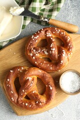 Wall Mural - tasty pretzels with salt and butter on light grey table, flat lay