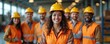 © Pete - Diverse team of smiling professionals wearing safety gear, including hard hats, vests, pose confidently in industrial factory setting. Unity, teamwork evident, representing skilled labor, modern