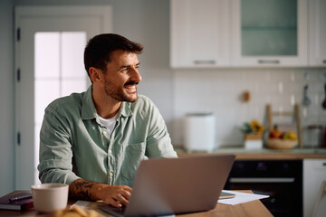 Happy man day dreaming while working on a computer at home.