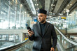 © Chanakon - Muslim asian businessman traveler holding boarding pass ticket, passport and smartphone at the airport terminal with luggage. Cheerful tourist islamic at airport holiday trip.