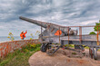 © EdNurg - Tourist pointing at an old Turkish military cannon overlooking the Dardanelles Strait in Turkey, exploring national heritage and historical defenses