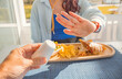© EdNurg - Woman making stop gesture with hand refusing salt shaker offered by waiter at a restaurant table with a plate of french fries, salad and wrap