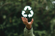 © Sumitra - Hand presents a glowing recycle symbol against a green background
