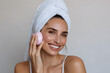 © Daniel - A beautiful woman is using a modern facial device for skincare treatment at home, enjoying self-care with a radiant smile and a soft towel on her head.