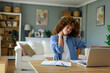 © Dorde - Young Woman with Curly Hair Experiencing Neck Pain While Working from Home in a Cozy Living Room