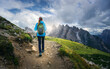 © den-belitsky - Young woman hiking along a mountain trail, carrying a backpack while savoring the breathtaking views of Tre Cime di Lavaredo and the stunning Dolomites landscape in Italy