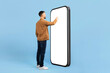 © Anastasiya - Back view of young man interacting with large blank smartphone screen. Ideal for futuristic app concepts, UX design, or touchscreen technology themes, collage