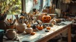 © Farida - A table is full of Halloween crafts in a sunny pottery studio. There are tools, brushes, and things being made.