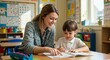 © Cintia - Teacher helps young student reading a book in a classroom, pointing to the page while the child looks at the words.