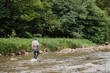 © dsheremeta - Fisherman wading in river, casting fishing rod in pristine nature