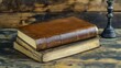 © akun - Antique leather-bound books stacked on a weathered wooden surface with candle holder