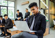 © Gatot - Focused Indian Businessman Working on Laptop with Colleagues Sitting in Co-working Room
