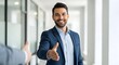 © yazidkautsar1 - A smiling businessman extends his hand for a handshake, welcoming someone in an office setting.