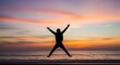 © helga - Silhouette of a joyful man jumping on the beach at sunset with arms raised
