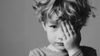 © Naufal - A young boy covering his face with his hand, expressing sadness and anxiety, mental health concept, emotional struggle, vulnerability, introspection, childhood stress.
