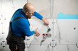 © Василь Івасюк - Man installing ceramic granite tiles on the wall in the new apartment. Plumber installing ceramic tile in customers bathroom, getting ready to sell home. Tile leveling system.