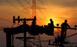 © apithana - silhouette group of electric worker on crane with the high voltage electric pole  background