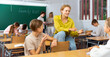 © JackF - Teenagers students of middle school chatting on break sitting at desks in classroom