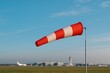 © michnik101 - Windsock extended in clear sky near runway and control tower, used in aviation for monitoring wind conditions