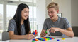 © AIHUN - Teenagers playing with colorful building blocks indoors and smiling