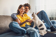 © djoronimo - Portrait of young happy couple and their cat at home. They are holding paw of the cat.