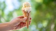 © You are the best - A hand holding a dripping vanilla ice cream cone against a blurred green and blue background