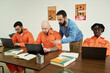 © pressmaster - Middle aged Caucasian man instructing group of adult men working on laptops in classroom setting, participating in educational program
