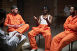 © pressmaster - Group of multiethnic male prisoners sitting in circle participating in group therapy session with counselor taking notes in prison setting