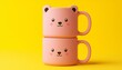 © Montalumirock - Kids cartoon two mug drink with pink animal face shape on solid copy space background