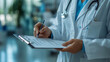 © Alex Alex - A nurse or doctor in a medical uniform who is writing information in a notebook. She is holding a pen and is filling out documentation or a medical record.