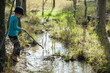 © Austockphoto - Young boy playing with a stick at the creek